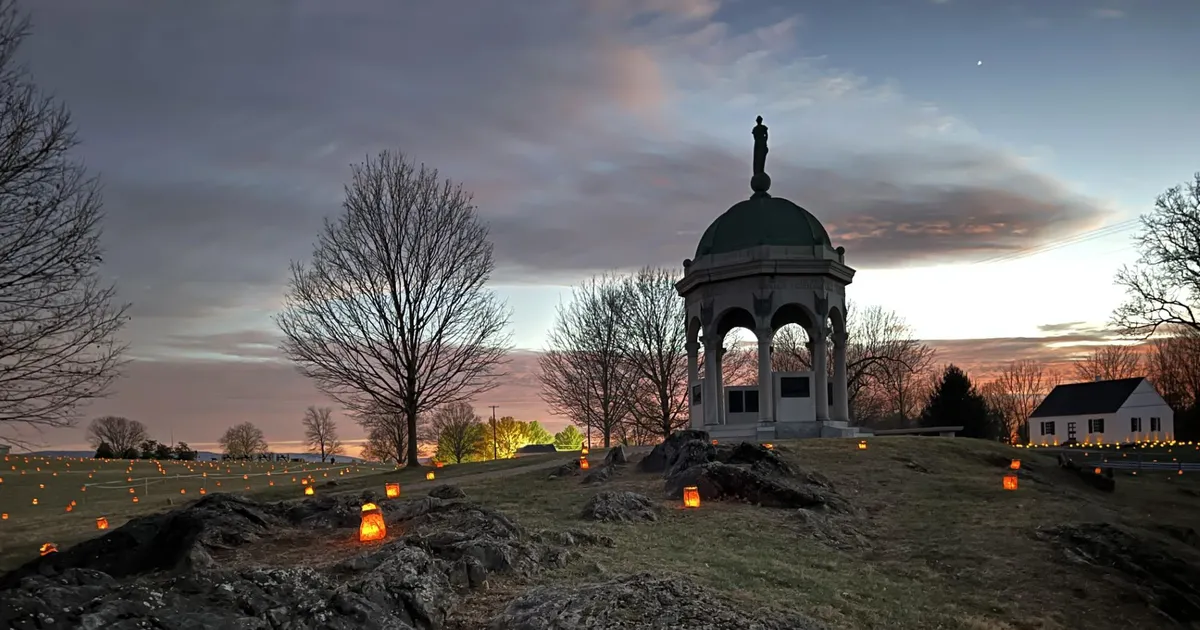 luminaries placed by Maryland Monument with dramatic orange red clouds
