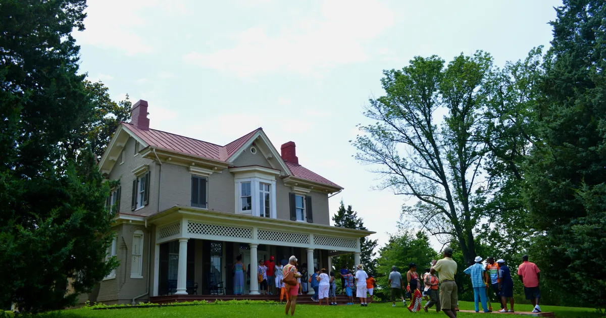 Visitors take photos in front of a historic house