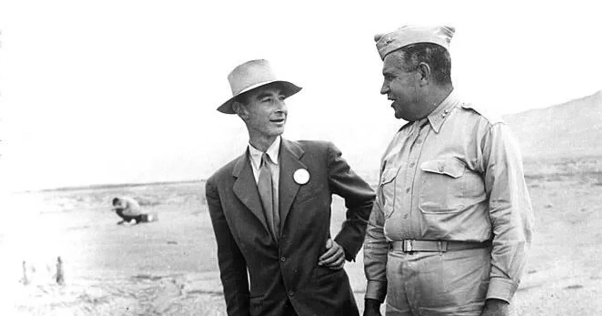 Historic photo of two men standing next to a mangled piece of metal equipment in the desert.