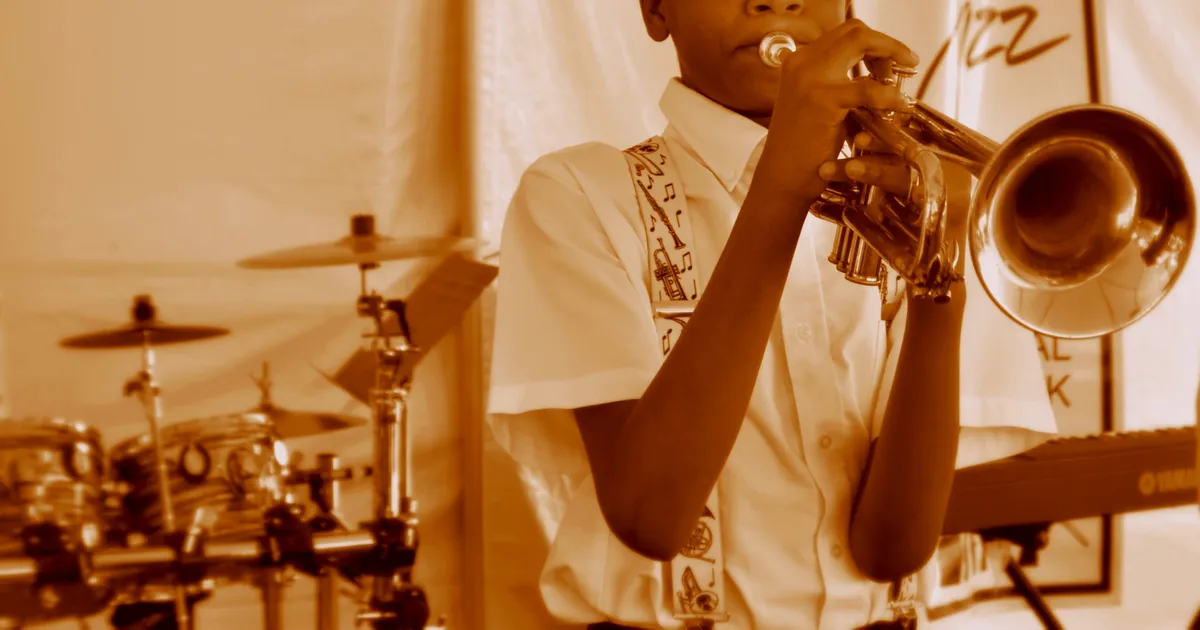 A young brass band musician plays a trumpet
