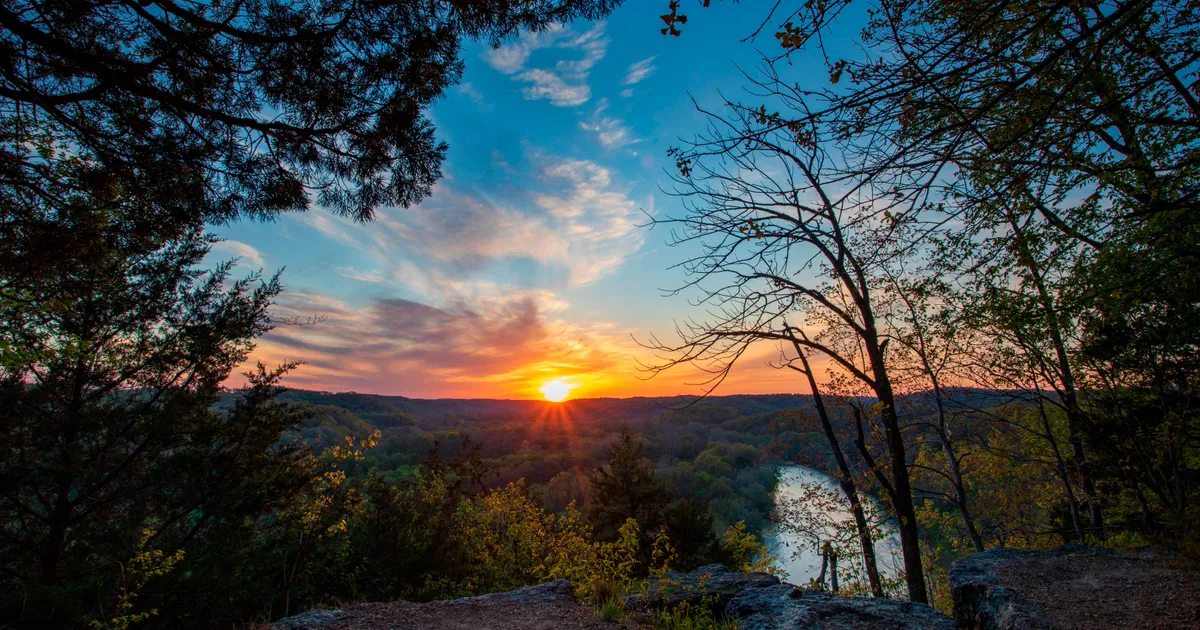 Sunset picture with high vantage point overlooking river with fall colors and sun setting in distanc